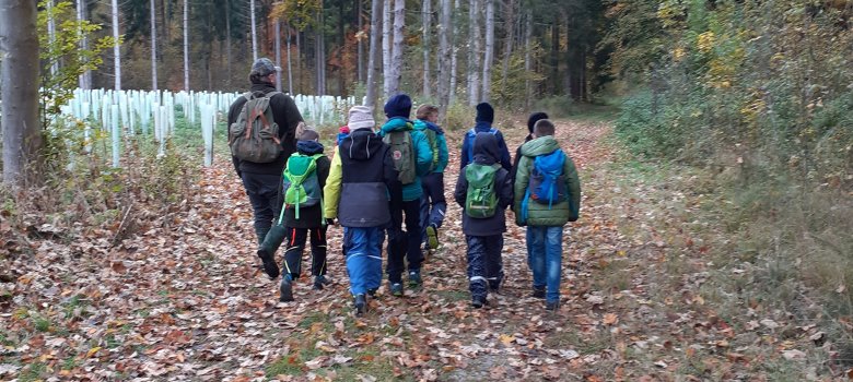 Eine Gruppe Kinder läuft mit einem Jäger durch den Wald